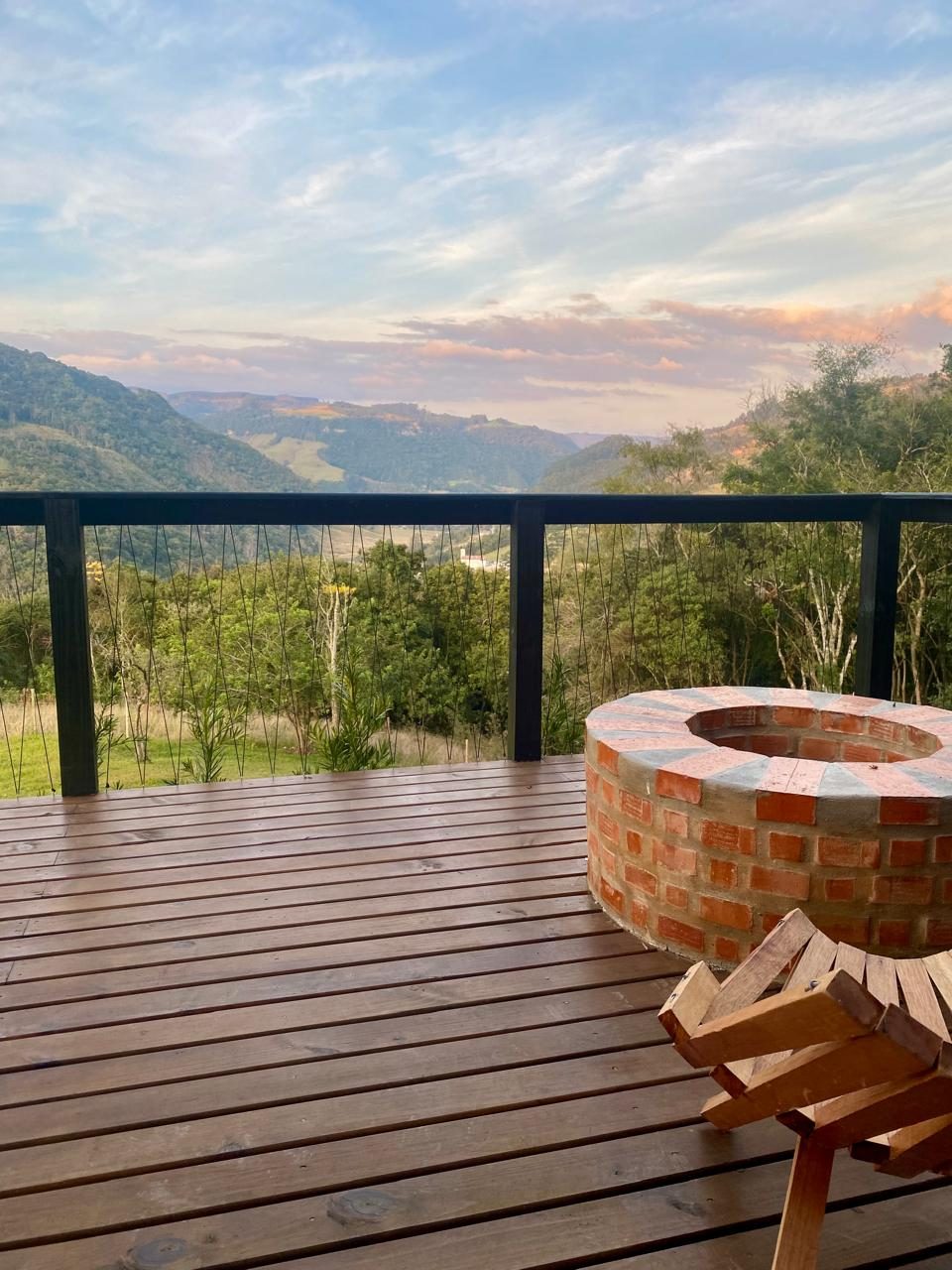 Deck de madeira com fogueira e vista para as montanhas ao entardecer