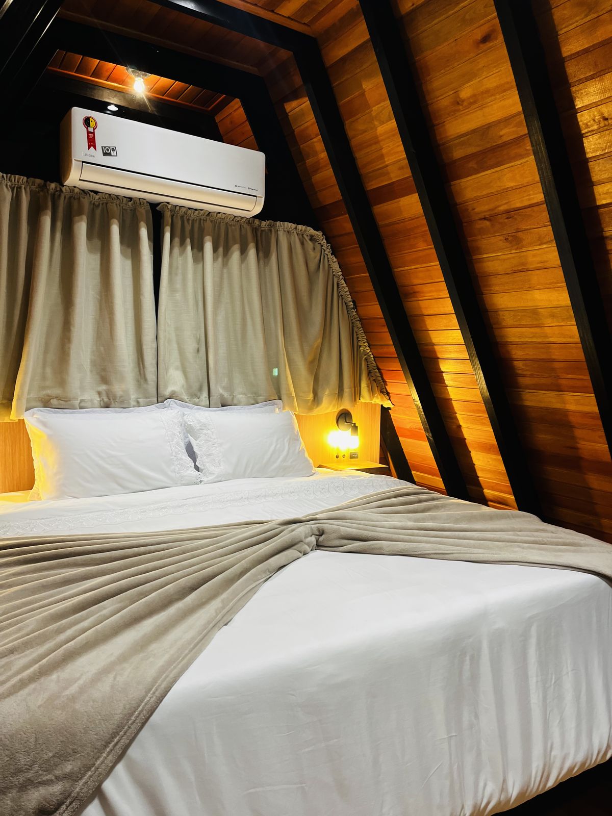 Quarto de casal com cama de casal, iluminação aconchegante e teto em madeira