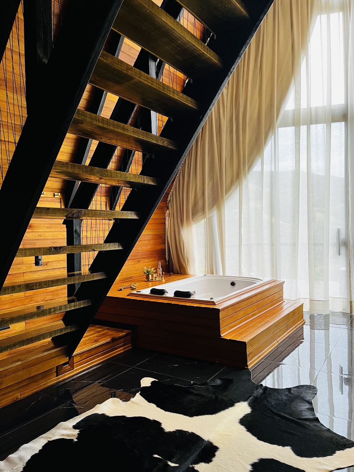 Escada de madeira e hidromassagem com tapete estilo boi em ambiente aconchegante