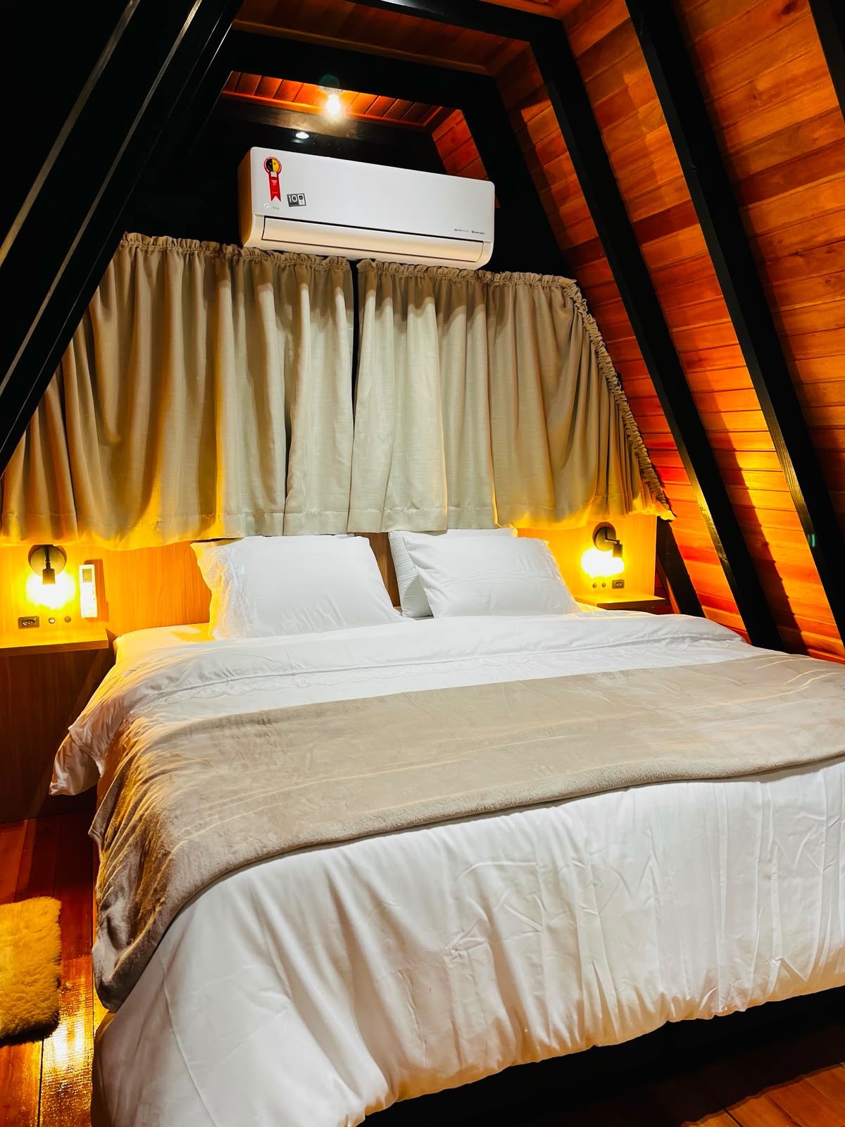 Quarto de casal com cama de casal, iluminação aconchegante e teto em madeira