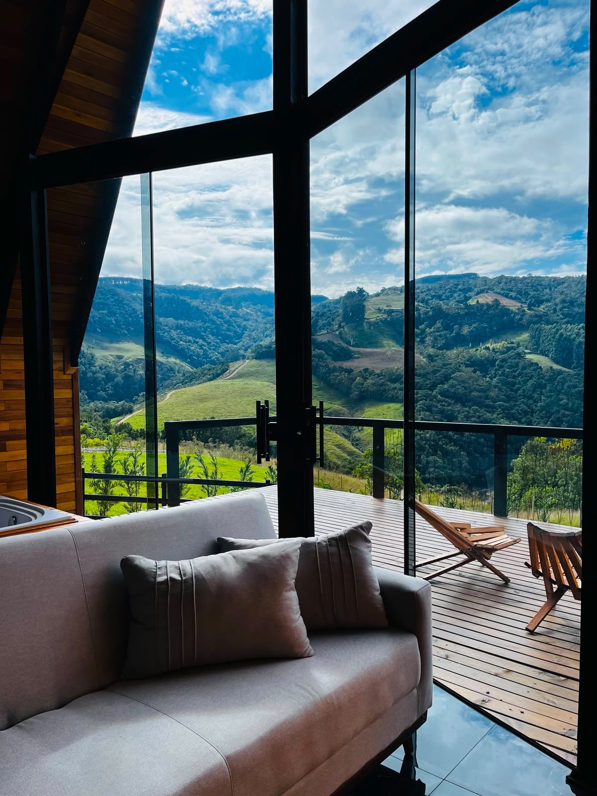 Sofá em frente ao janelão com vista panorâmica para o vale da Serra Catarinense